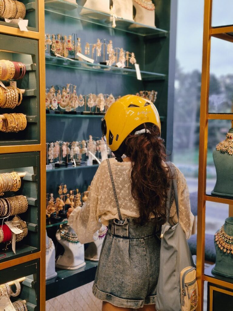 A woman wearing a yellow helmet looking at a display of jewelry